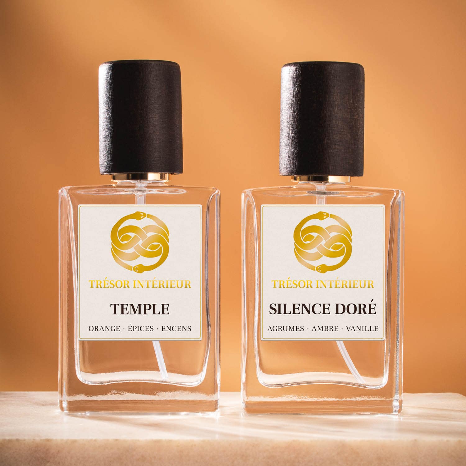 Deux flacons de spray parfum d’intérieur Trésor Intérieur : « Temple » et « Esprit Libre » 30ml, sur fond orange.