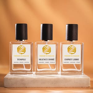 Trois flacons de spray parfum d’intérieur Trésor Intérieur : « Temple », « Esprit Libre » et « Silence Doré » 30ml, sur fond orange.